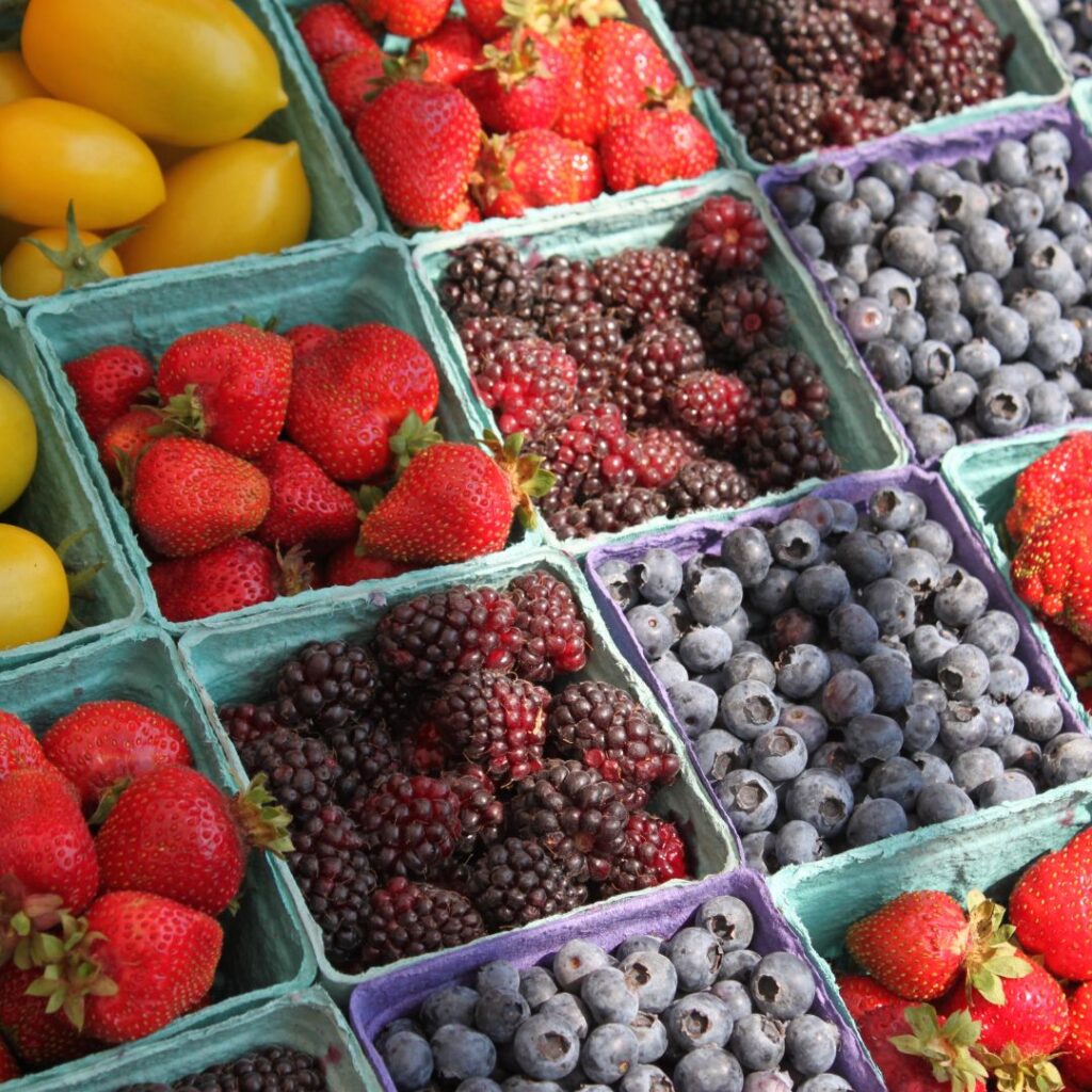 Variety of berries such as strawberries, blueberries, and blackberries separated by containers.