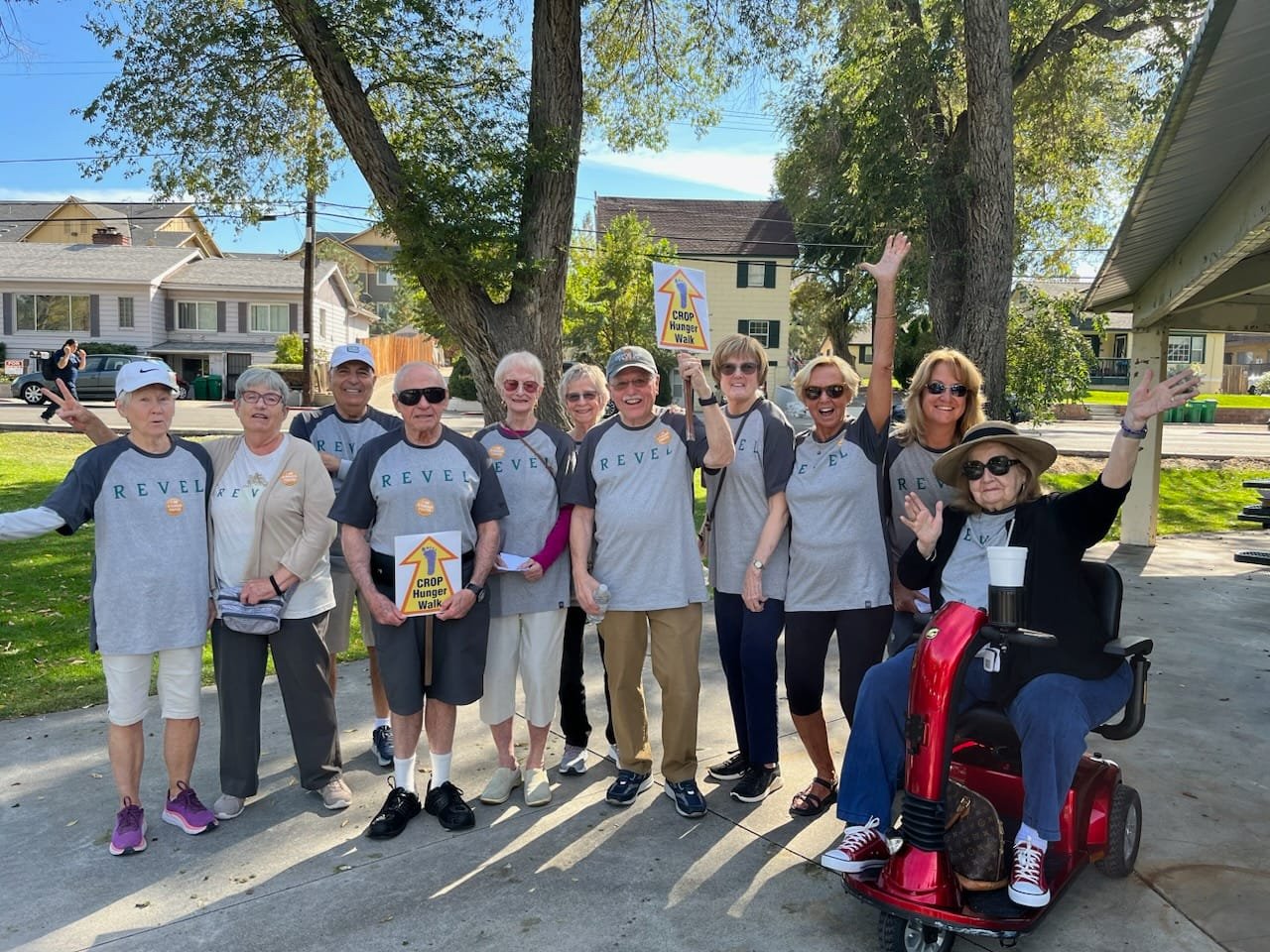 A group of smiling community participants gathered outdoors together at the CROP Hunger Walk.